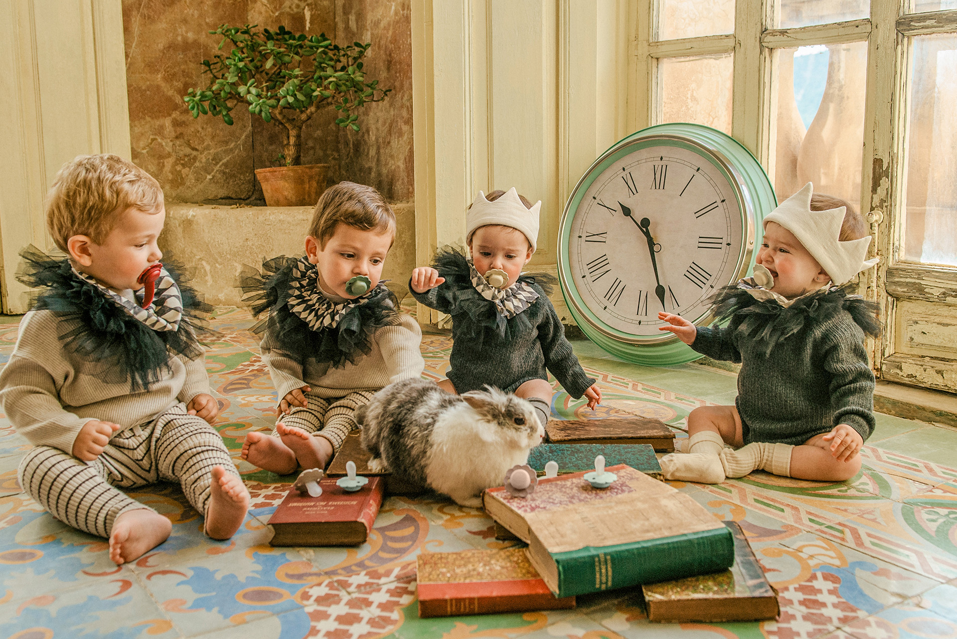 Bebés jugando con un conejo y con libros
